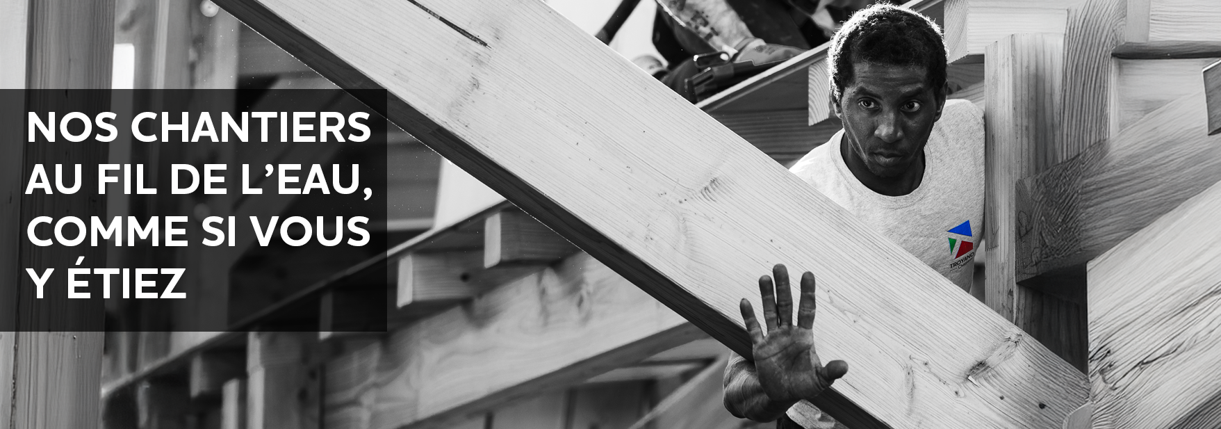 charpentier Troyano Charpente portant une pièce de bois sur chantier de charpente