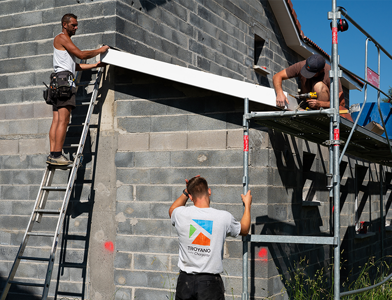 équipe Troyano Charpente posant une sablière sur mur en parpaing lors d'une construction neuve