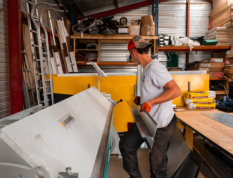 zingueur Troyano Charpente façonnant une pièce de zinc en atelier sur plieuse
