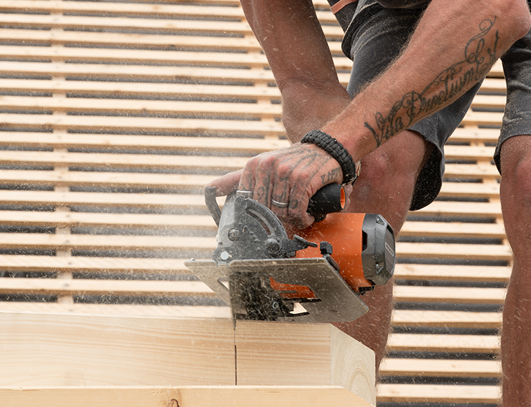 charpentier couvreur découpant du bois au disque sur chantier de toiture