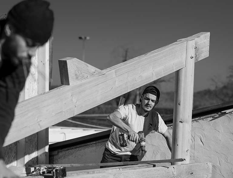 charpentier vissant une pièce de charpente bois à la visseuse sur chantier de construction