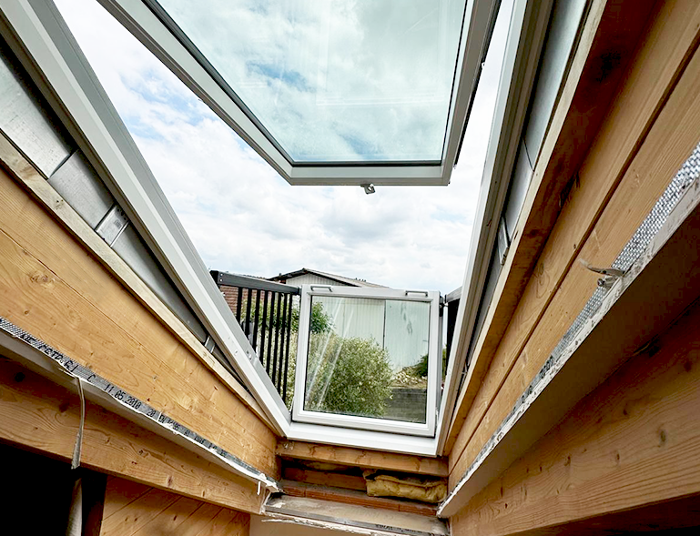 fenêtre de toit Velux cabrio ouverte en position balcon vue depuis l'intérieur sur ossature bois neuve