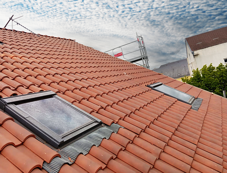 pose de fenêtres de toit Velux en cours sur toiture en tuile rouge avec échafaudage